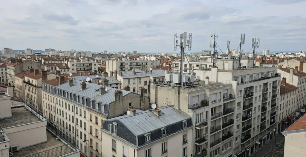 Vue grand angle d'un paysage urbain français contemporain avec installations d'antennes cellulaires visibles sur les toits, architecture moderne, lumière d'après-midi Vue grand angle d'un paysage urbain français contemporain avec installations d'antennes cellulaires visibles sur les toits, architecture moderne, lumière d'après-midi