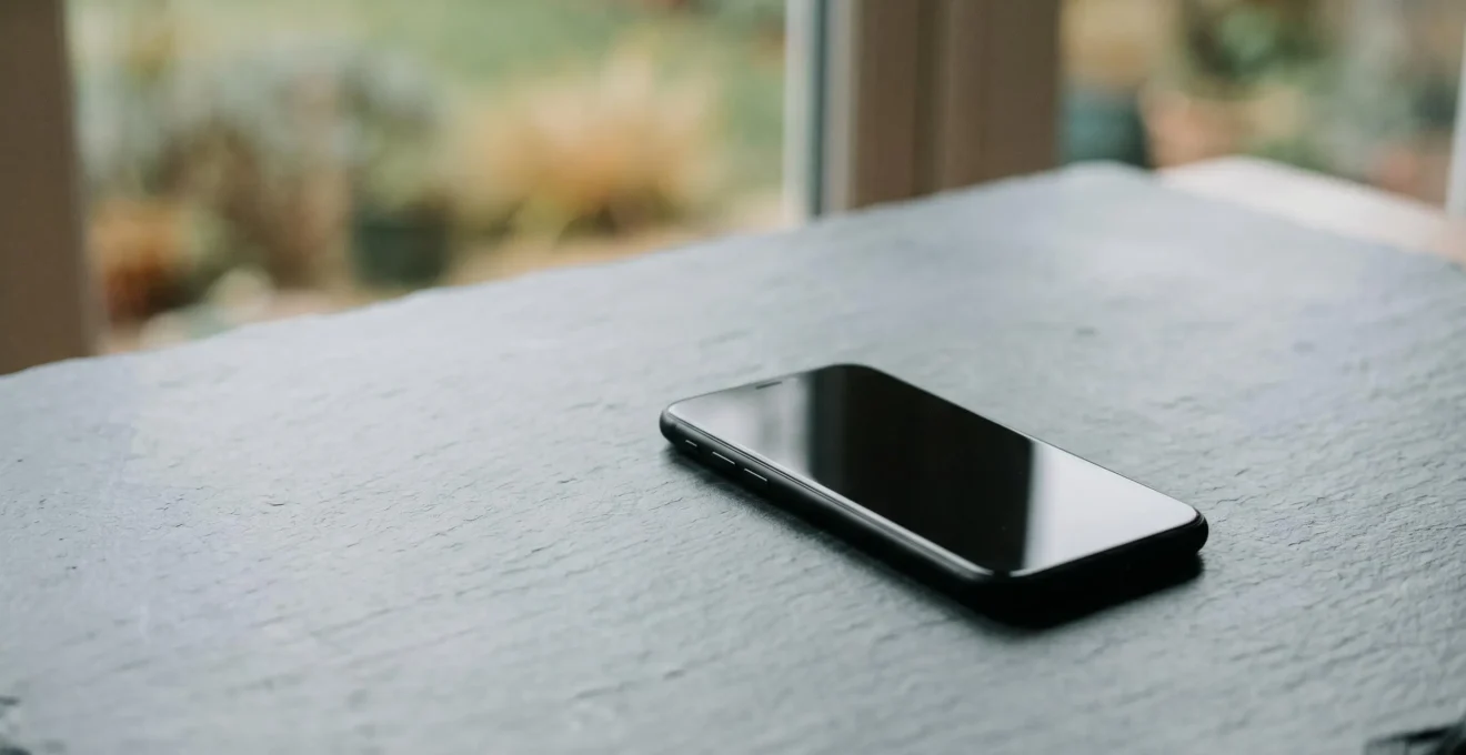 Smartphone sur fond minimaliste illustrant le concept de bilan carbone et durabilité technologique