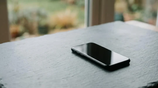 Smartphone sur fond minimaliste illustrant le concept de bilan carbone et durabilité technologique
